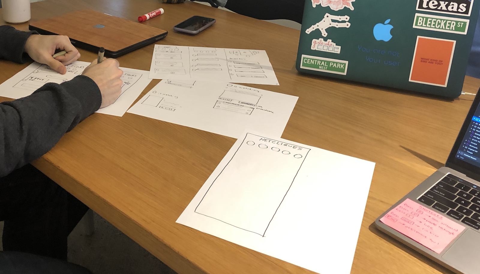 Hands sketching NetCliques ideas during the participatory design studio